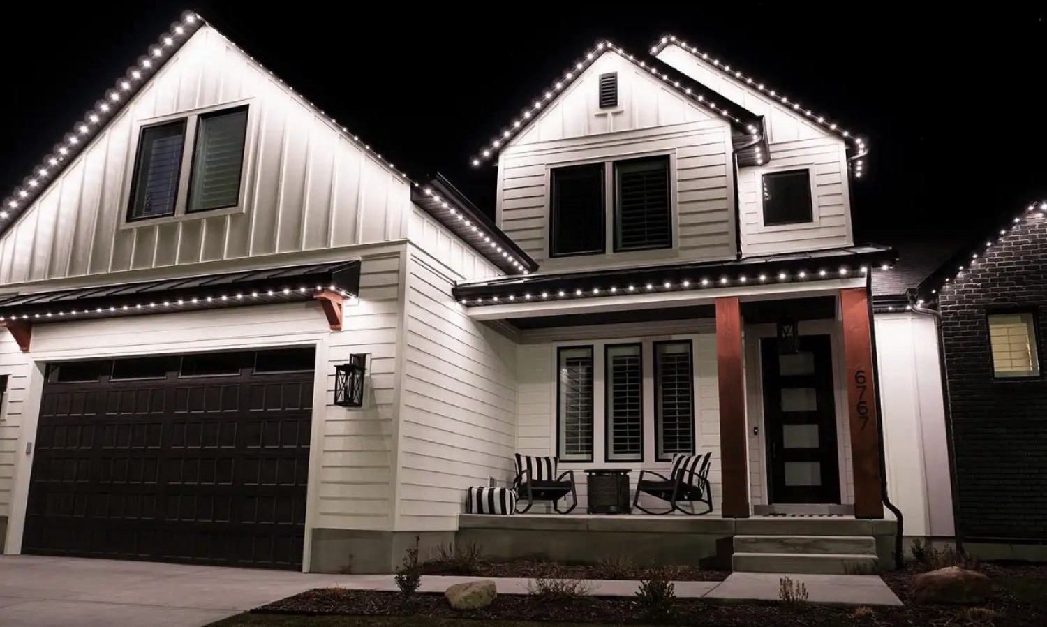 Warm white C9s on a white farmhouse with a dark garage and porch